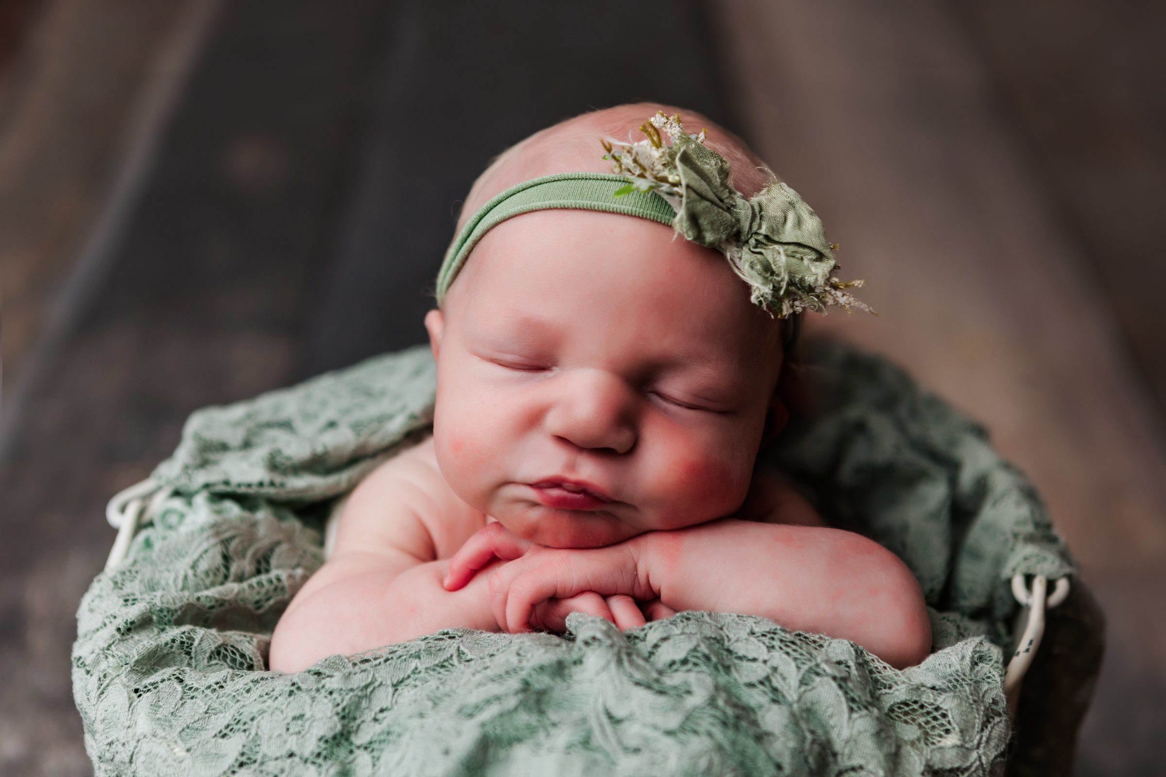newborn girl with head on hands