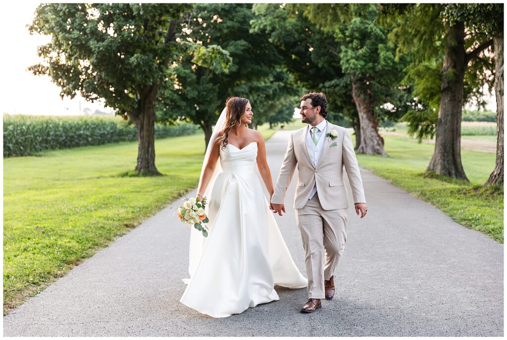 bride and groom walking tree lined road at Reid's Orchard